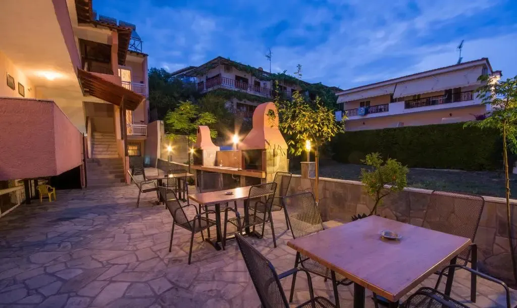 Terrasse avec tables et chaises près d'un barbecue en pierre.