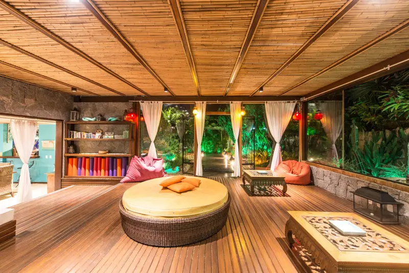 Espace de détente extérieur avec mobilier en rotin et coussins colorés.