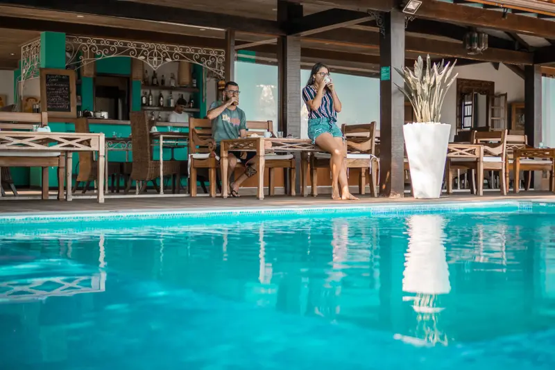 Des clients prennent un petit-déjeuner au bord d'une piscine turquoise.