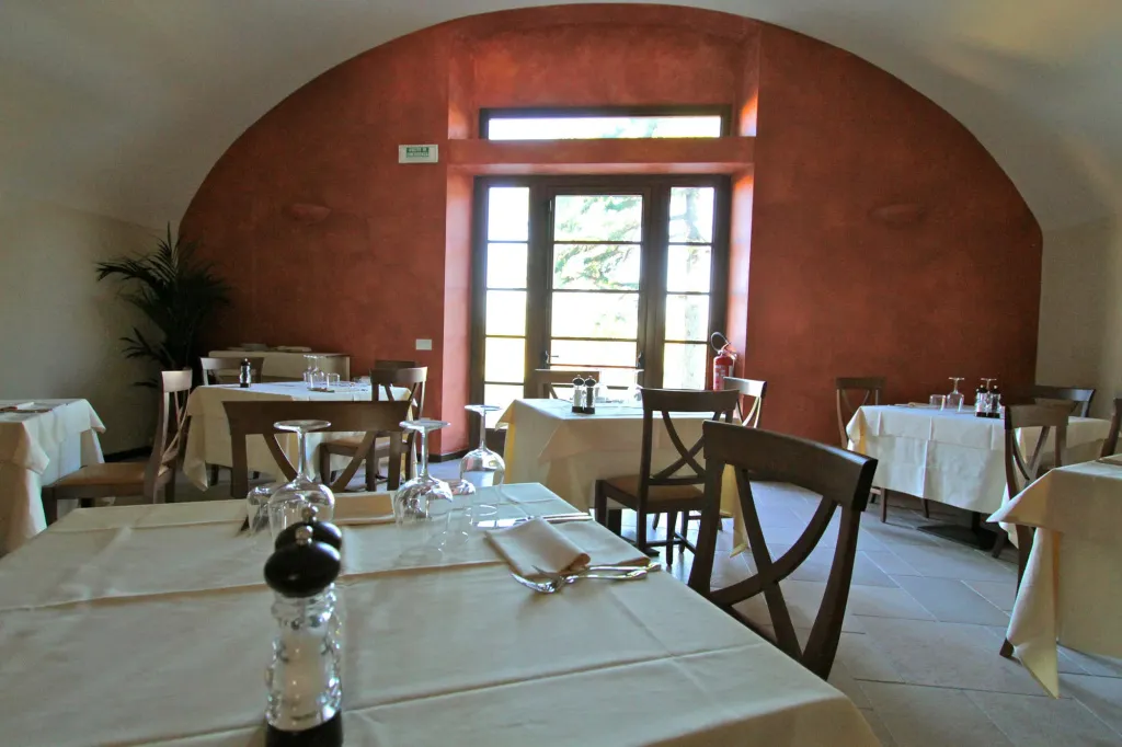 Une salle de restaurant avec des tables nappées et une fenêtre ouverte sur l'extérieur.