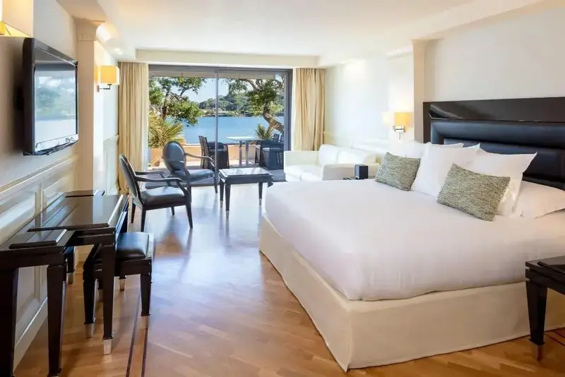 Une chambre lumineuse avec un lit king-size et un accès à une terrasse avec vue sur la mer.