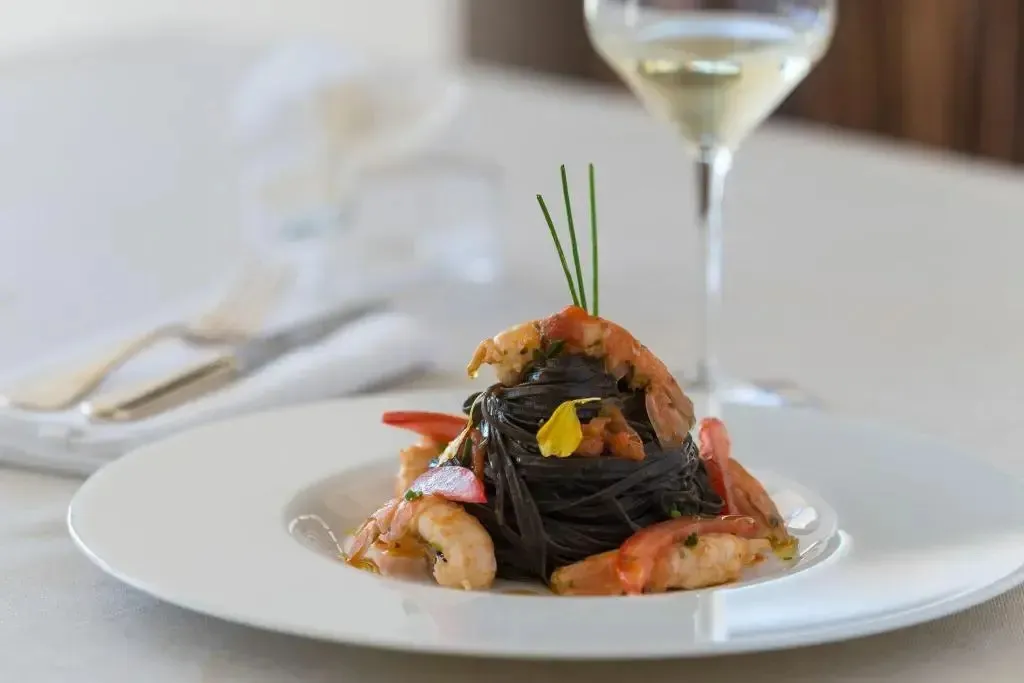 Assiette de pâtes noires aux crevettes et au vin blanc.