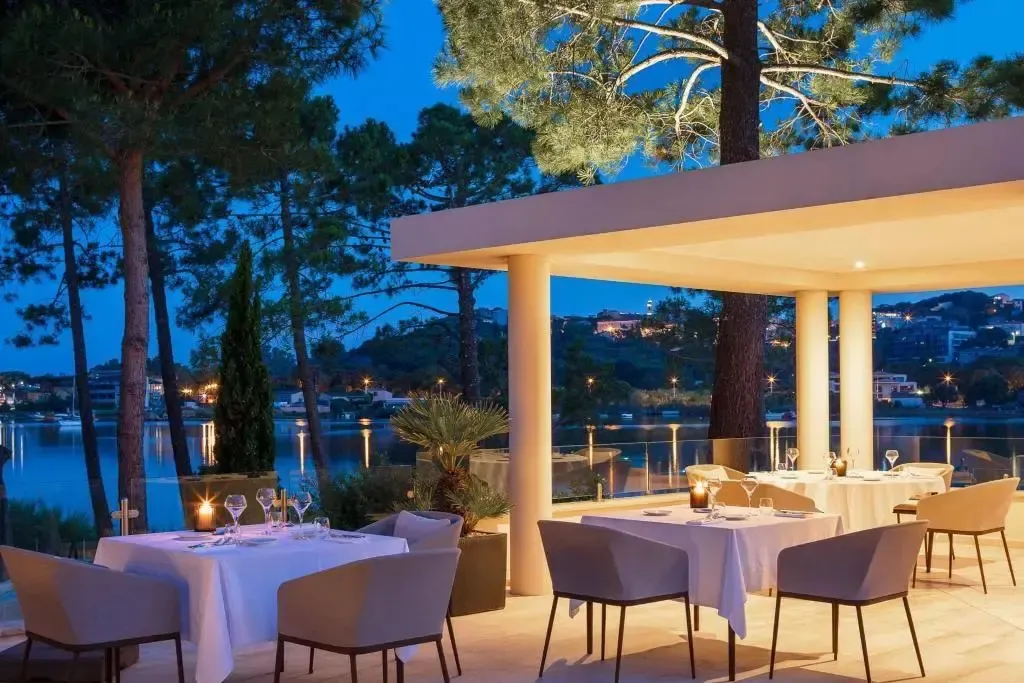 Tables dressées en terrasse avec vue sur la mer au crépuscule.