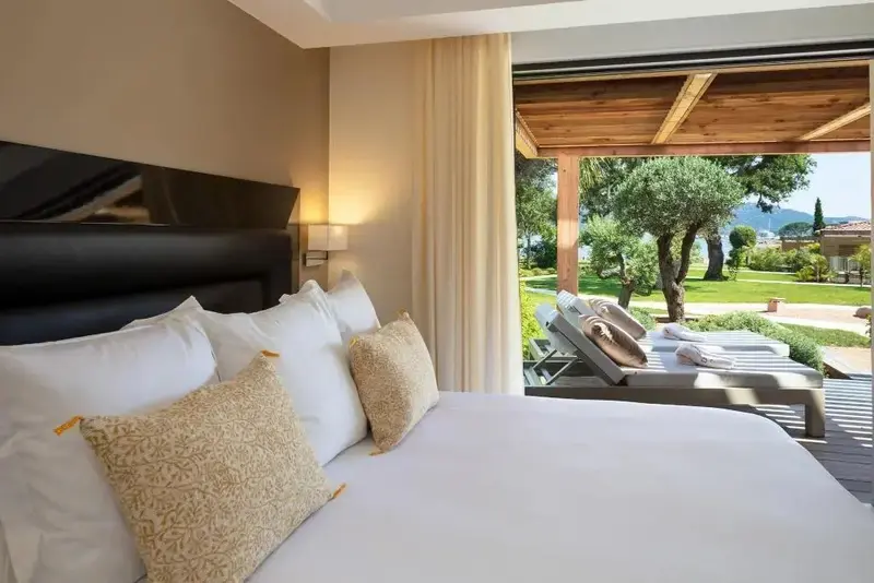 Une chambre lumineuse s'ouvre sur une terrasse aménagée avec des chaises longues.