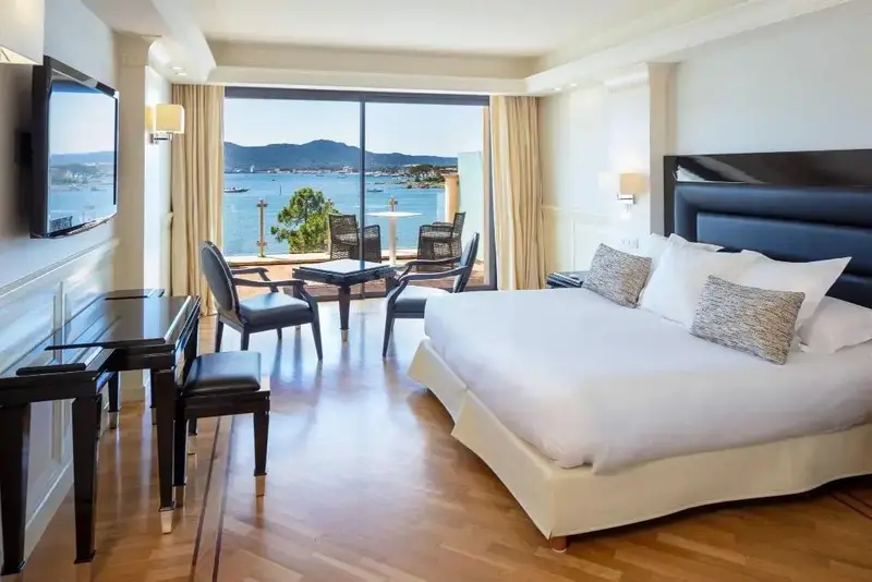 Une chambre lumineuse avec un lit double et un espace détente donnant sur la mer.