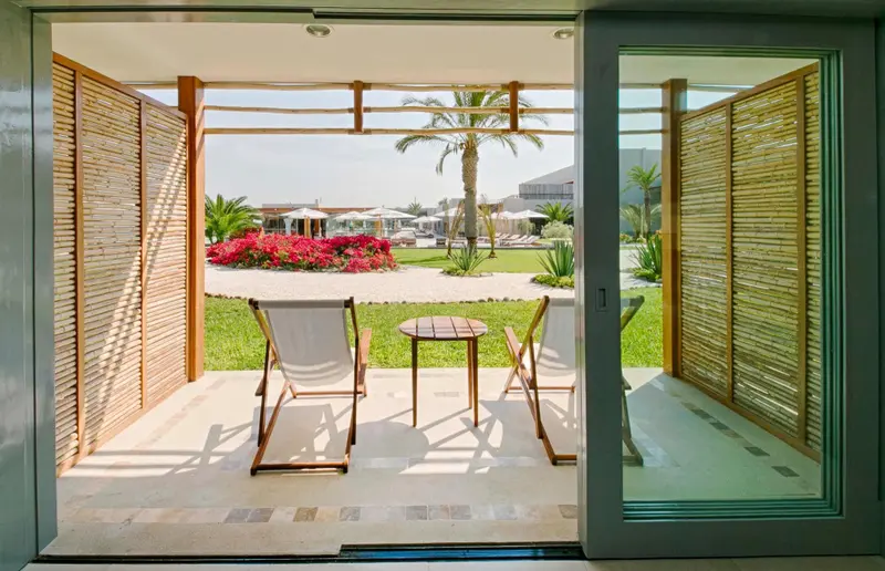 Terrasse aménagée avec deux fauteuils et une petite table basse, donnant sur un jardin soigné.