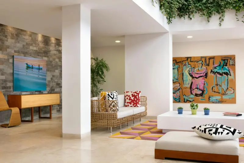 Un espace de vie lumineux avec un canapé coloré et des œuvres d'art murales.