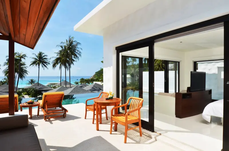 Terrasse aménagée avec mobilier de jardin donnant sur une piscine et la mer.
