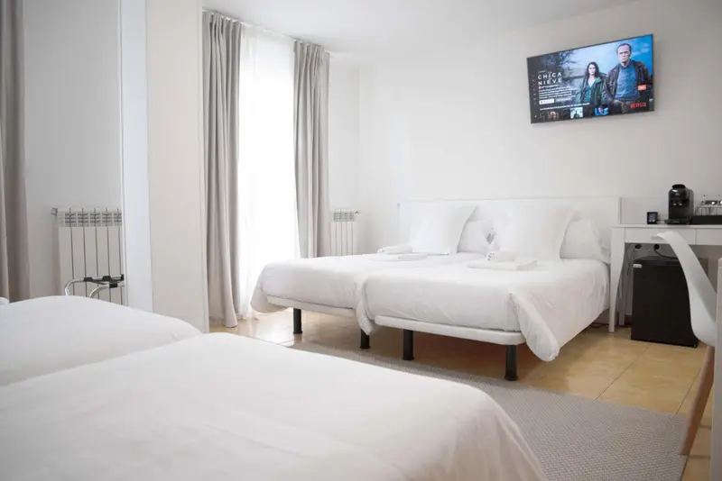 Une chambre lumineuse avec deux lits simples et un lit double.
