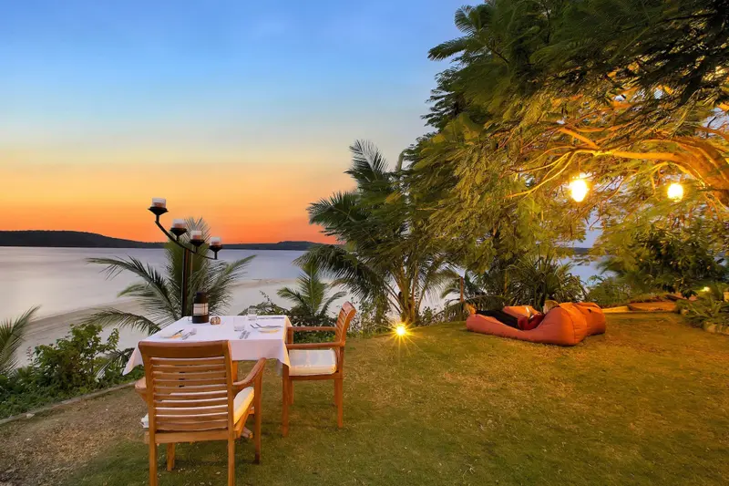 Table dressée pour un dîner en extérieur avec vue sur la mer au coucher du soleil.