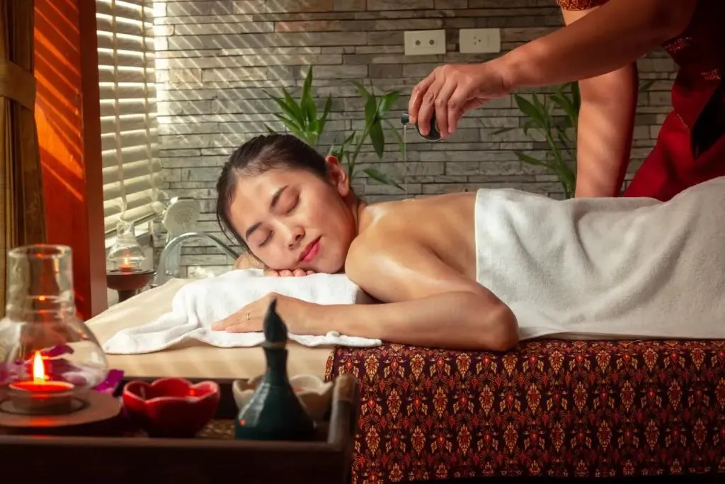 Une femme allongée reçoit un massage relaxant dans une ambiance chaleureuse.
