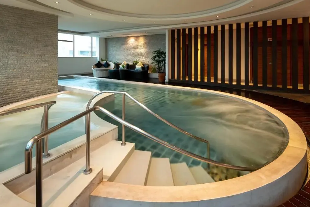 Une piscine intérieure avec des escaliers et un espace détente.