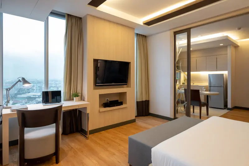 Une chambre lumineuse avec un espace bureau et une kitchenette attenante.