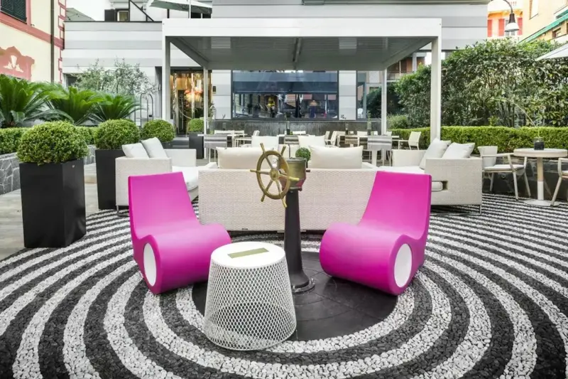 Espace de détente extérieur avec mobilier coloré et sol en mosaïque.