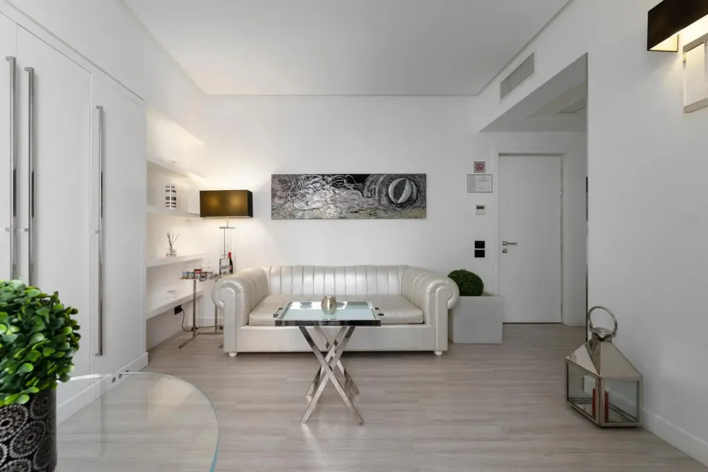 Un salon clair avec un canapé blanc et une table basse en verre.