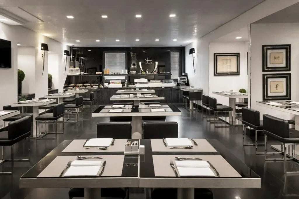 Une salle de restaurant moderne avec des tables dressées et un comptoir de buffet en fond.