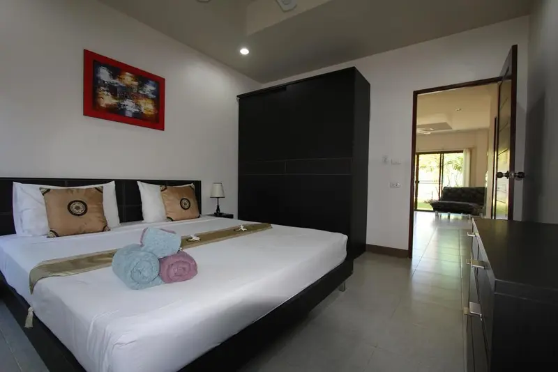 Une chambre lumineuse avec un grand lit et un espace salon ouvert sur l'extérieur.