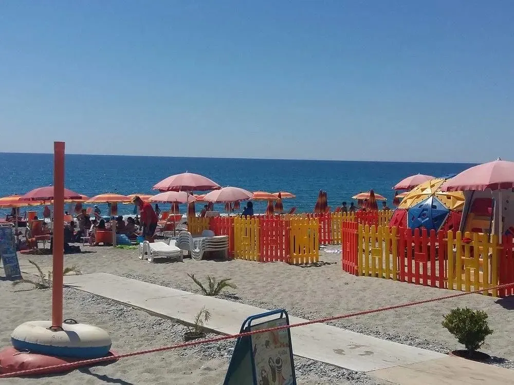 Plage ensoleillée avec parasols colorés et transats.
