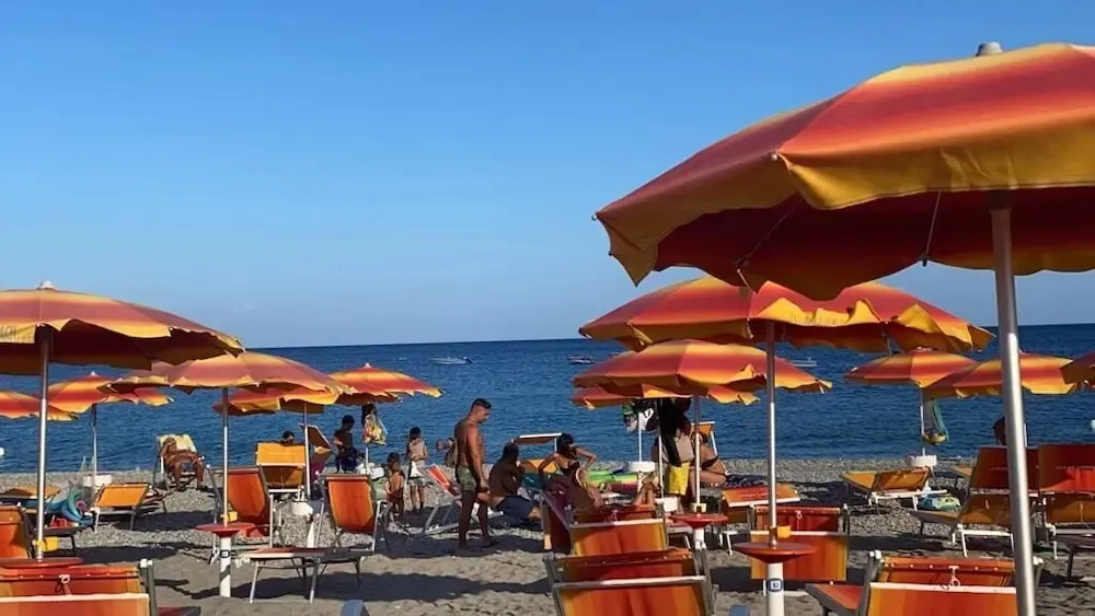 Une plage ensoleillée avec des parasols colorés et des transats.