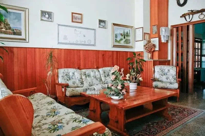 Un salon chaleureux avec des canapés en bois et des tableaux décoratifs.