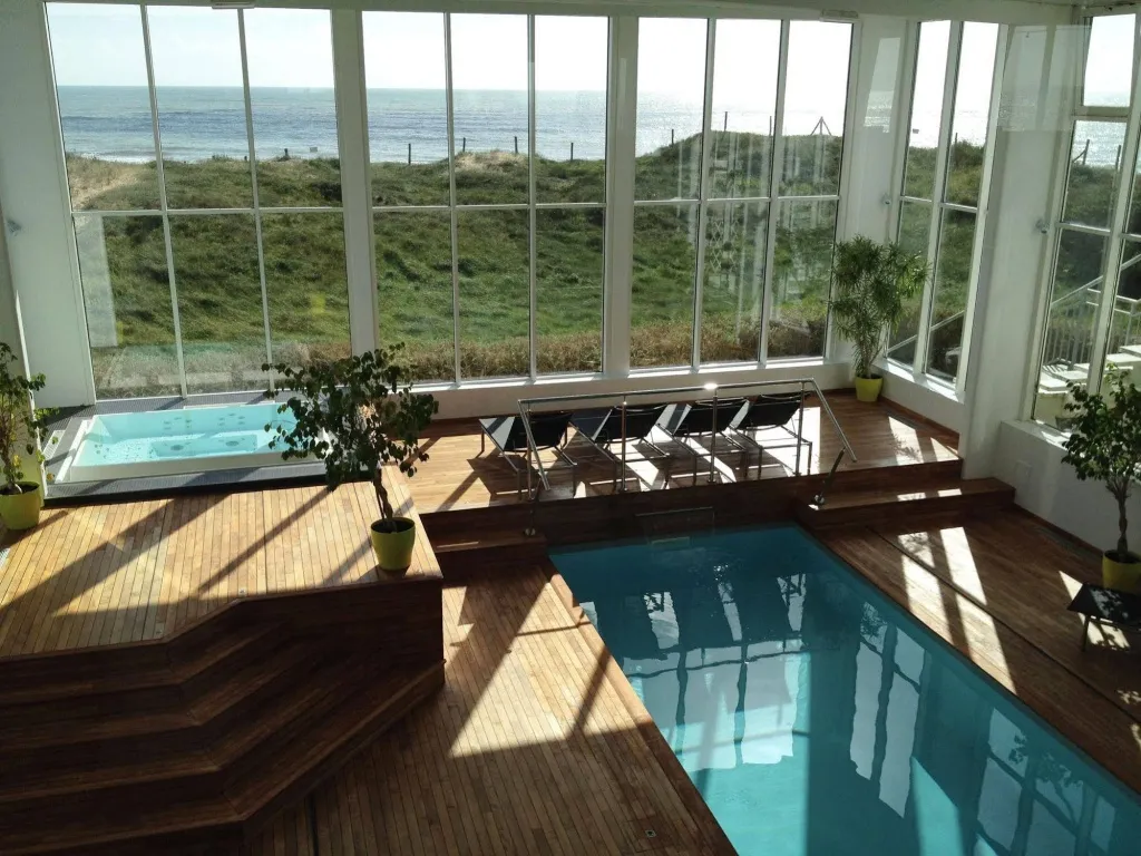 Espace baignade intérieur avec piscine et vue sur la mer.