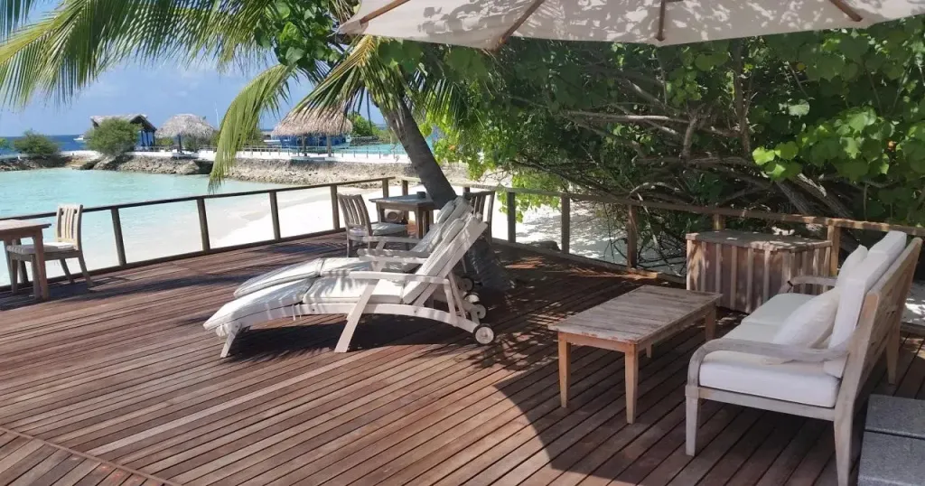 Terrasse en bois avec mobilier de détente et vue sur la mer.