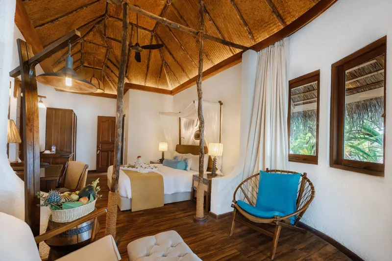 Une chambre lumineuse avec un lit à baldaquin et une décoration tropicale.