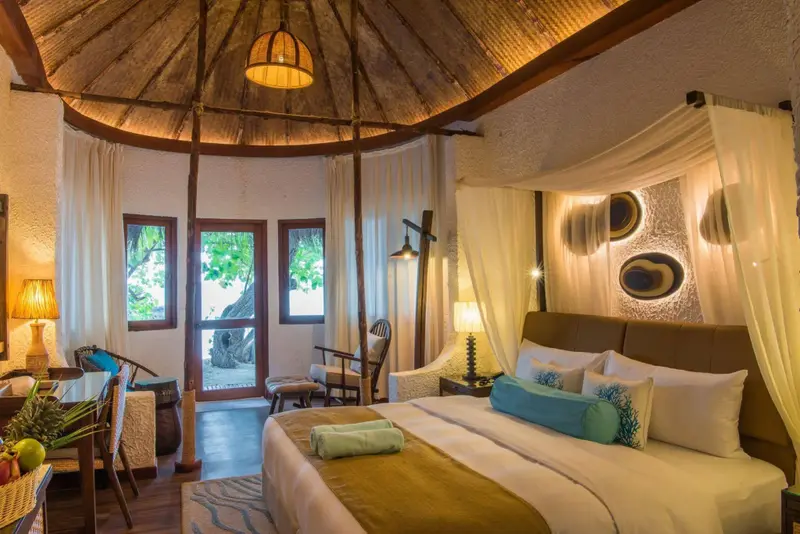 Une chambre lumineuse avec un lit à baldaquin et une vue sur la végétation.