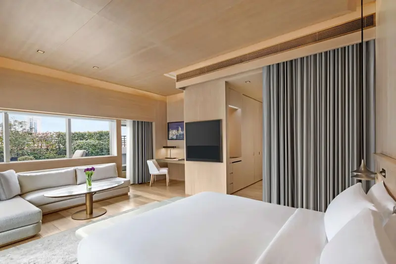 Une chambre lumineuse avec un canapé et un lit face à une grande fenêtre.
