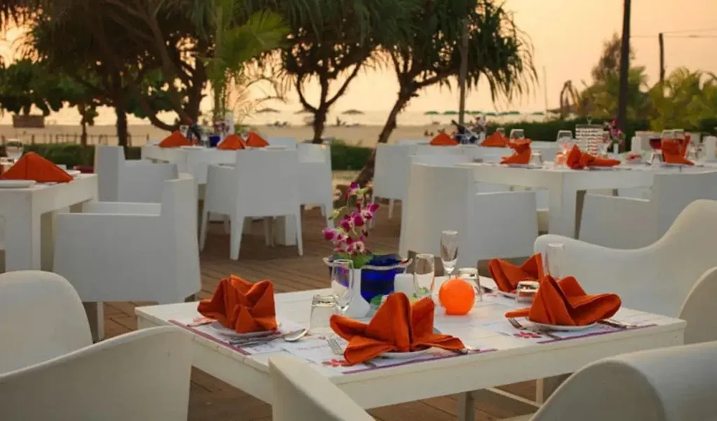 Tables dressées en terrasse face à la mer au coucher du soleil.