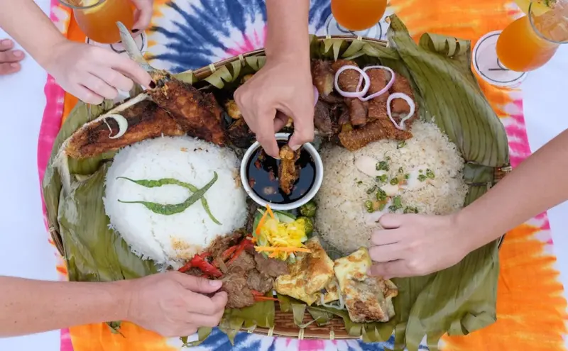 Une vue aérienne d'un plat copieux composé de riz, de poisson et de viande, servi sur des feuilles de bananier.