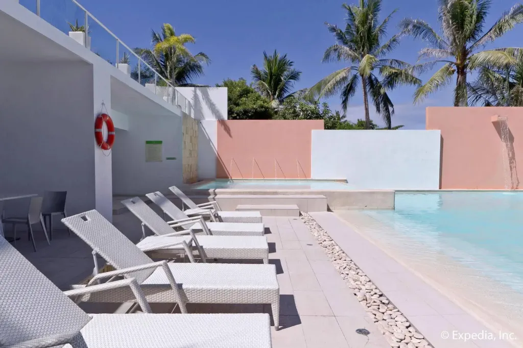 Transats blancs alignés au bord d'une piscine turquoise.