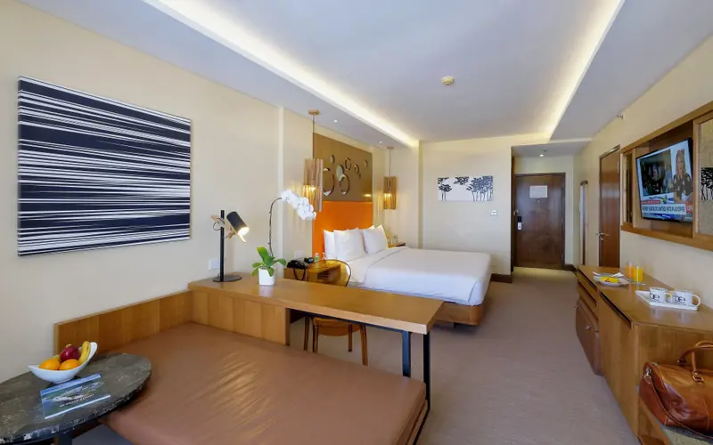 Une chambre lumineuse avec un lit double et un coin salon.