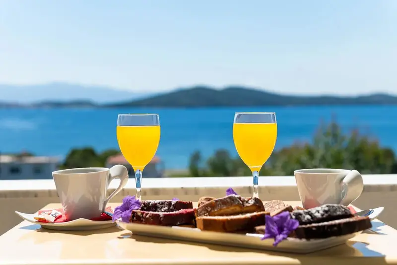 Un petit-déjeuner est servi sur une table avec vue sur la mer et les îles.