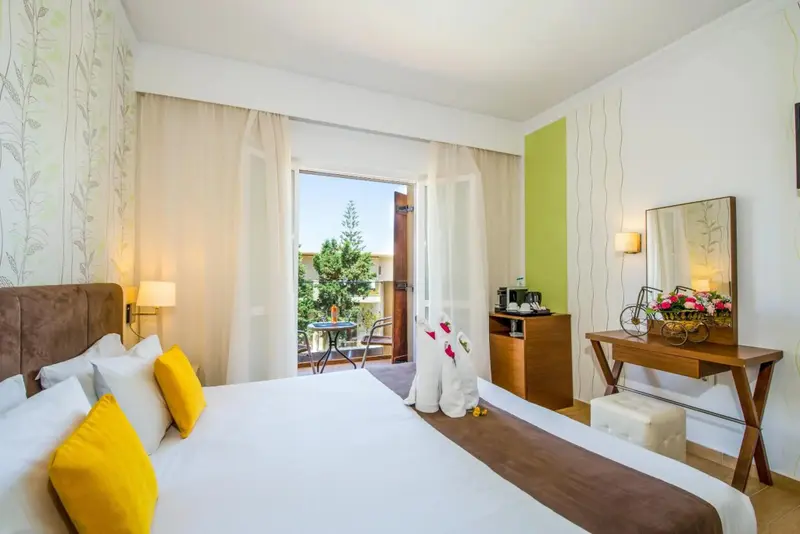 Une chambre lumineuse avec un grand lit et un accès à un balcon.