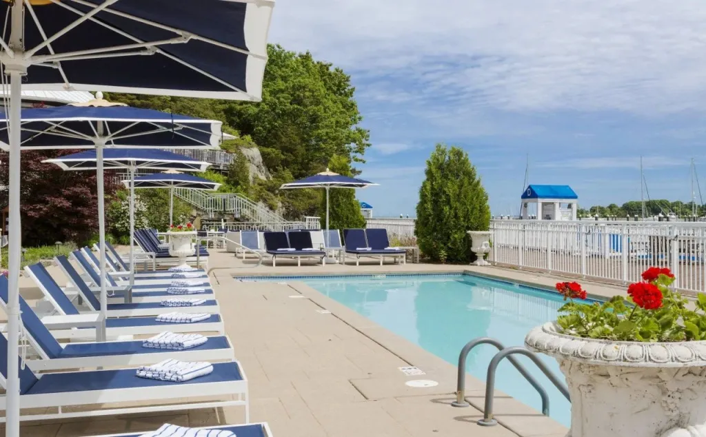 Transats bleus alignés au bord d'une piscine ensoleillée avec vue sur la mer.