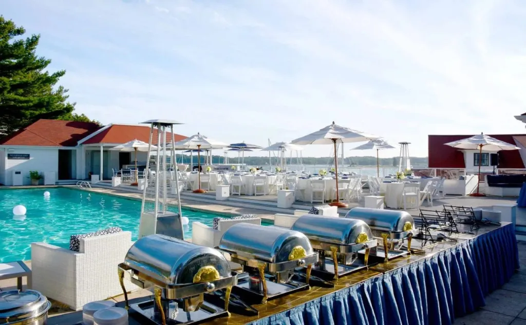 Une terrasse avec une piscine et un buffet de plats chauds.