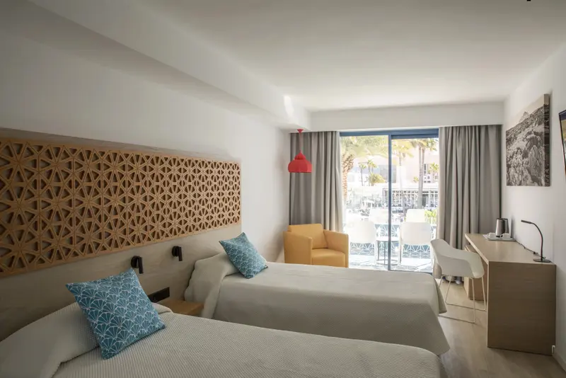 Une chambre lumineuse avec deux lits et un accès à une terrasse.