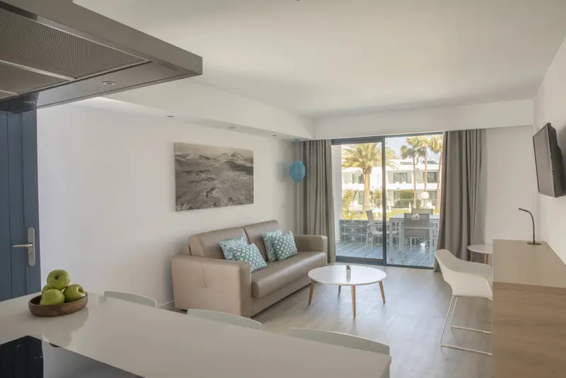 Un espace de vie lumineux avec canapé, table basse et accès à une terrasse.