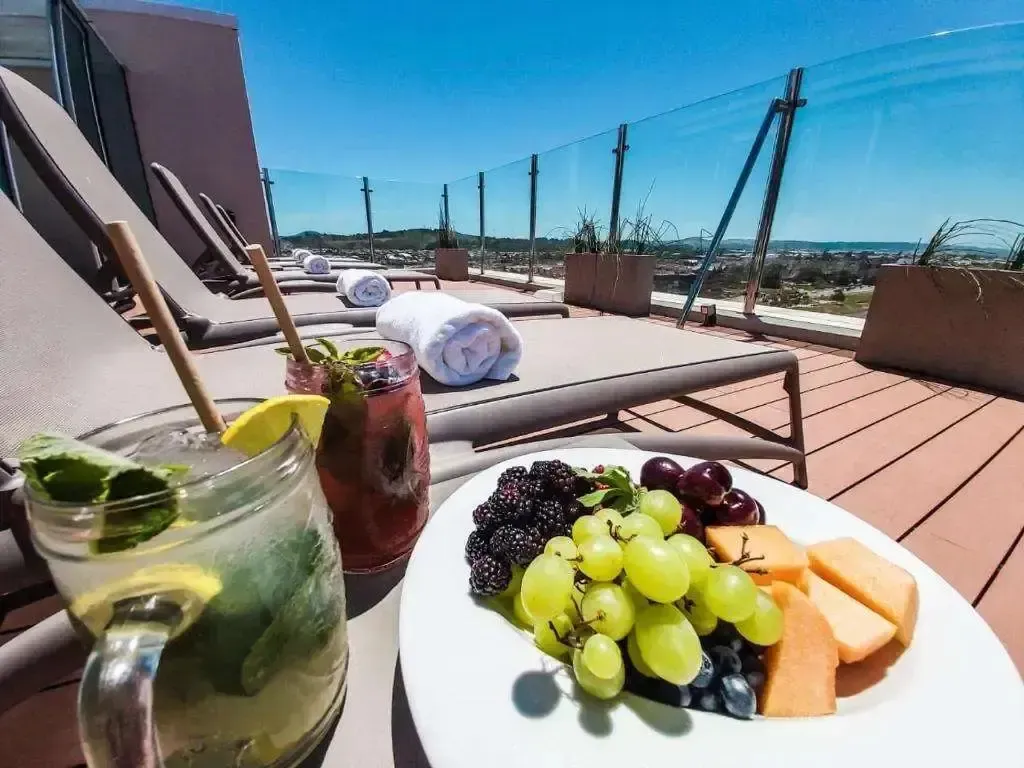 Transats et table basse avec boissons et fruits frais sur une terrasse ensoleillée.