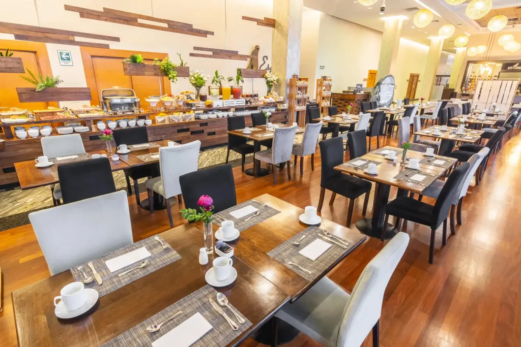 Une salle lumineuse est aménagée avec des tables dressées pour le repas.