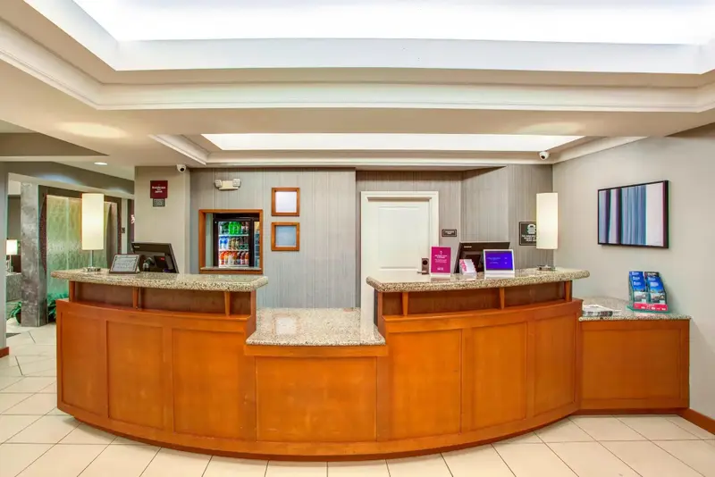 Un comptoir d'accueil en bois clair dans un hall d'hôtel.