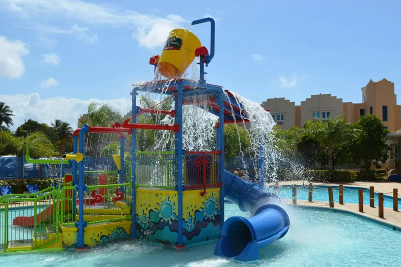 Structure de jeux d'eau colorée avec toboggan et seau basculant dans une piscine.