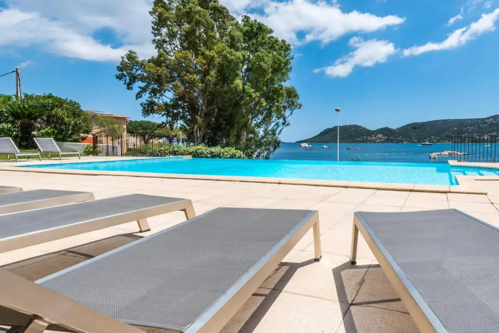 Transats au bord d'une piscine avec vue sur la mer et la côte.