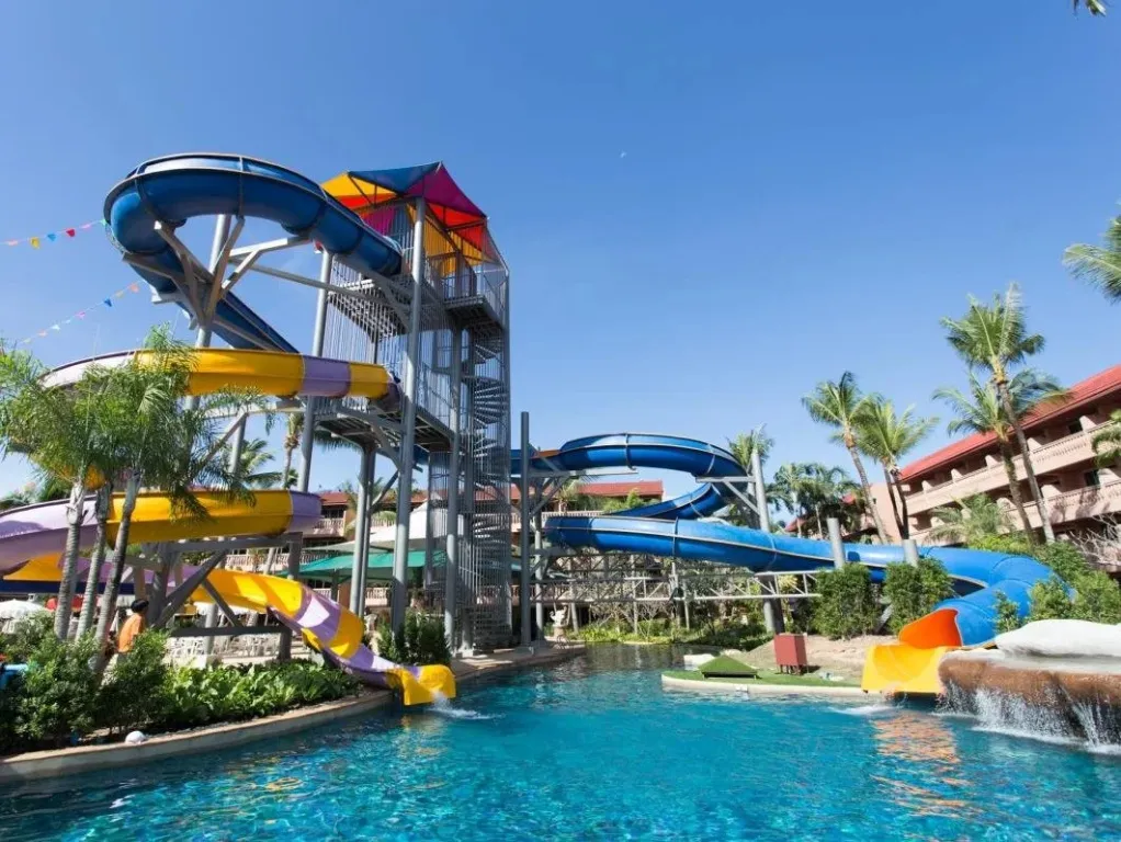 Une piscine avec des toboggans colorés et des palmiers.