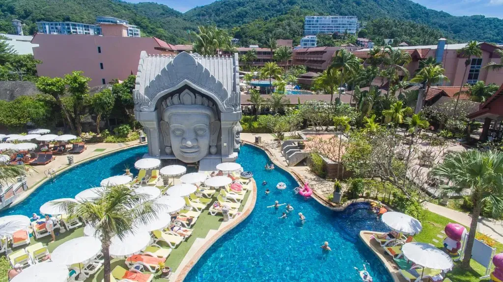 Une piscine sinueuse avec des transats et un grand visage sculpté.