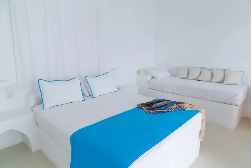 Une chambre lumineuse avec un lit et un canapé blanc.