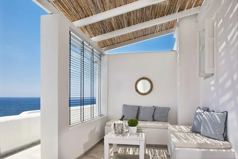 Espace de détente extérieur avec canapé et vue sur la mer.