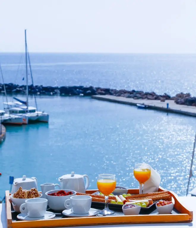 Un plateau de petit-déjeuner est présenté sur une terrasse avec vue sur un port de plaisance.