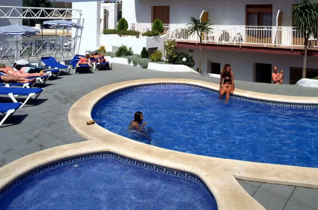 Une piscine avec des personnes se relaxant au soleil sur des transats.